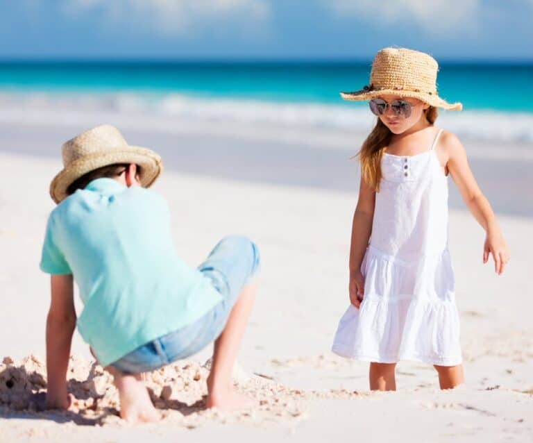 A couple of people that are standing in the sand on a beach