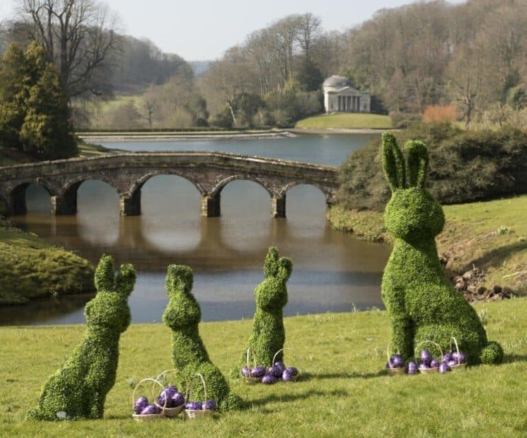 A garden with water in the background with Stourhead in the background