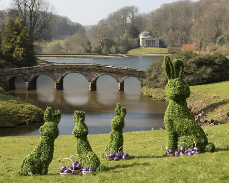 A garden with water in the background with Stourhead in the background