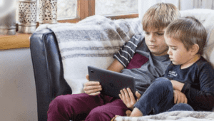 A young boy using a laptop computer sitting on top of a chair