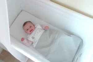 A baby sleeping next to a tub