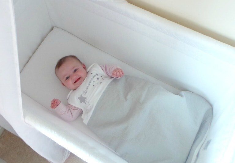 A baby sleeping next to a tub