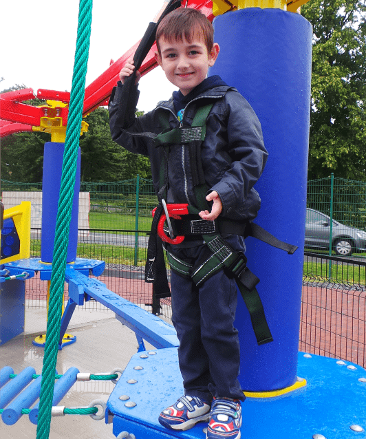 A little boy standing in front of a playground