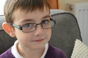 A close up of a boy wearing glasses and smiling at the camera