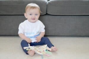 A small child sitting on a couch holding a baby