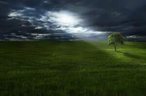 A large green field with clouds in the sky