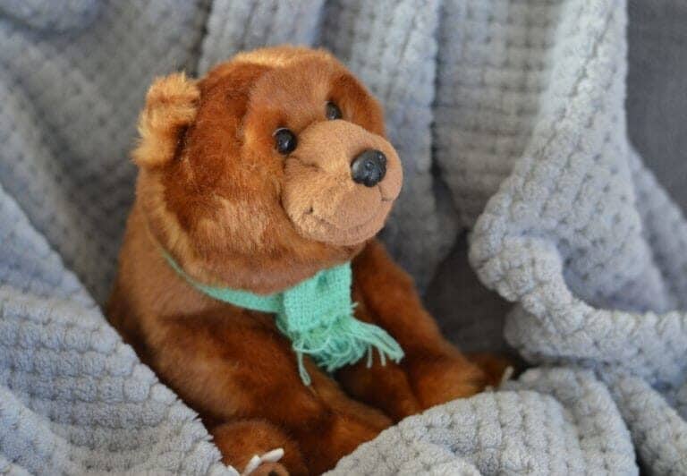 A large brown teddy bear sitting on top of a bed