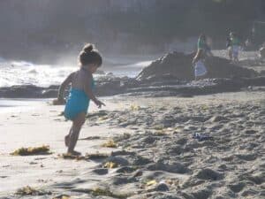 A little boy that is standing in the sand on a beach