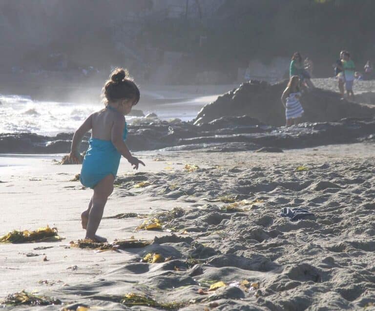 A little boy that is standing in the sand on a beach