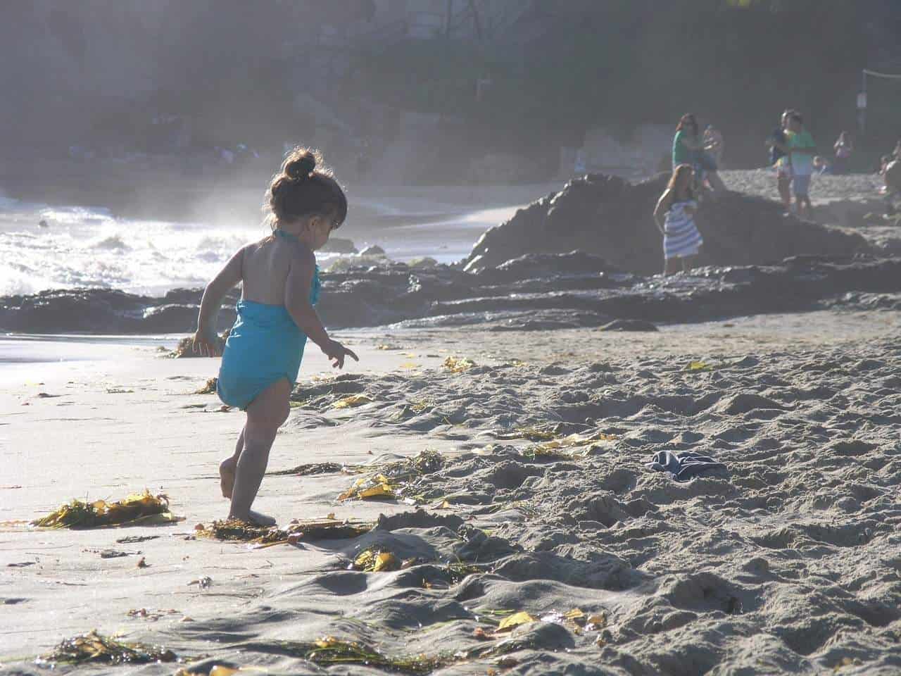 A little boy that is standing in the sand on a beach