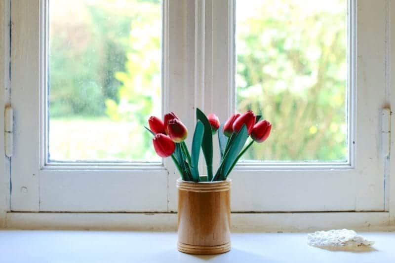 A vase of flowers sitting on a ledge in front of a window