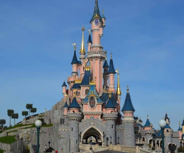 A castle with a clock at the top of Disneyland Paris