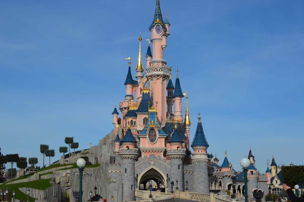 A castle with a clock at the top of Disneyland Paris