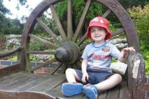 A little boy sitting on a wooden bench