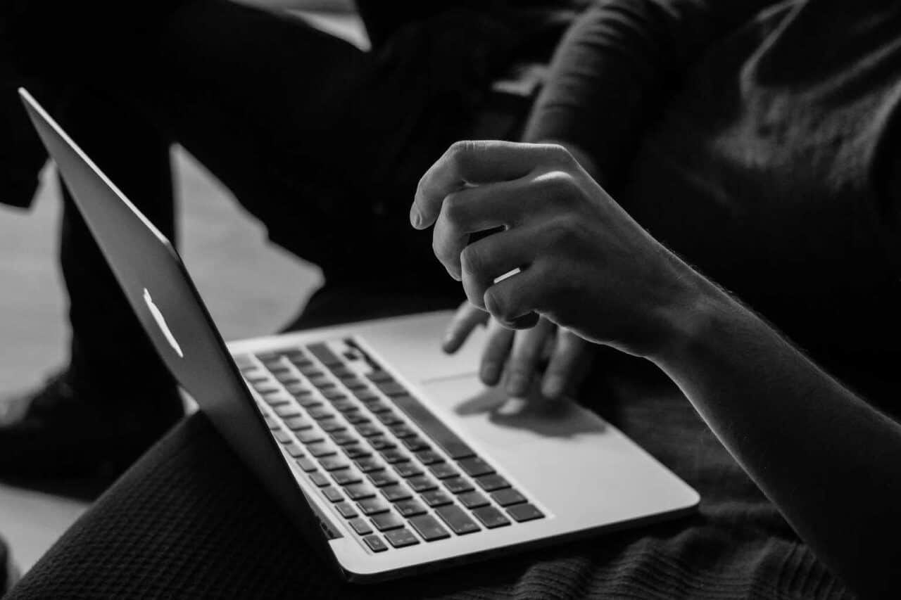 A person using a laptop computer sitting on top of a table