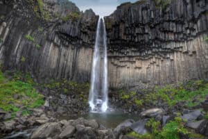 A large waterfall next to a rock wall