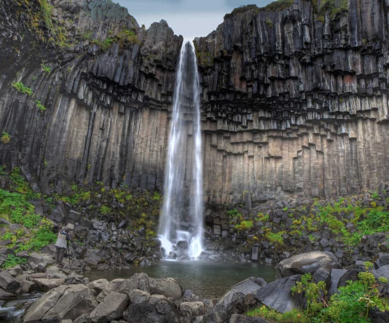 A large waterfall next to a rock wall