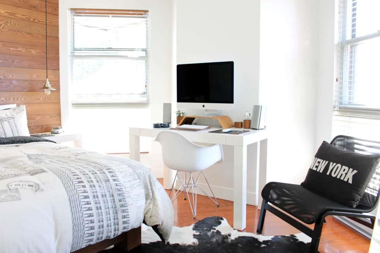 A bedroom with a bed and desk in a room