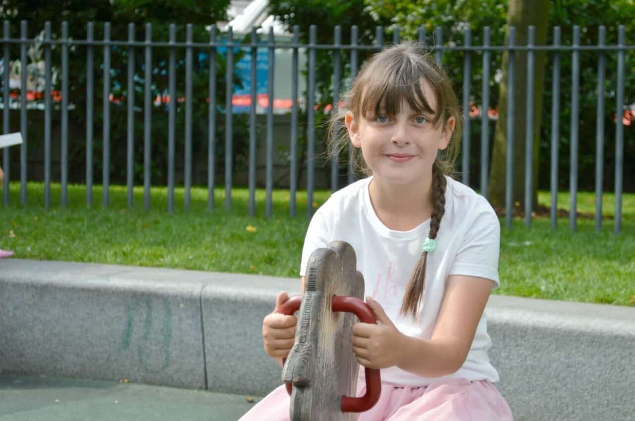 A little girl sitting at a zoo