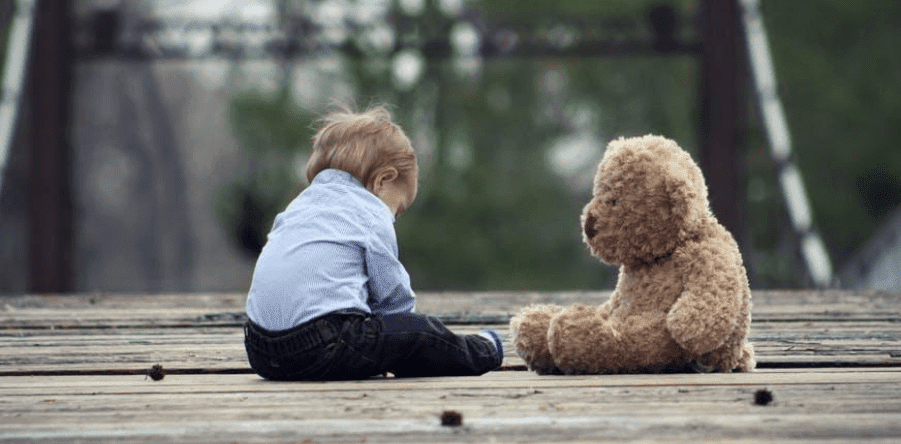 A teddy bear sitting on top of a wooden fence