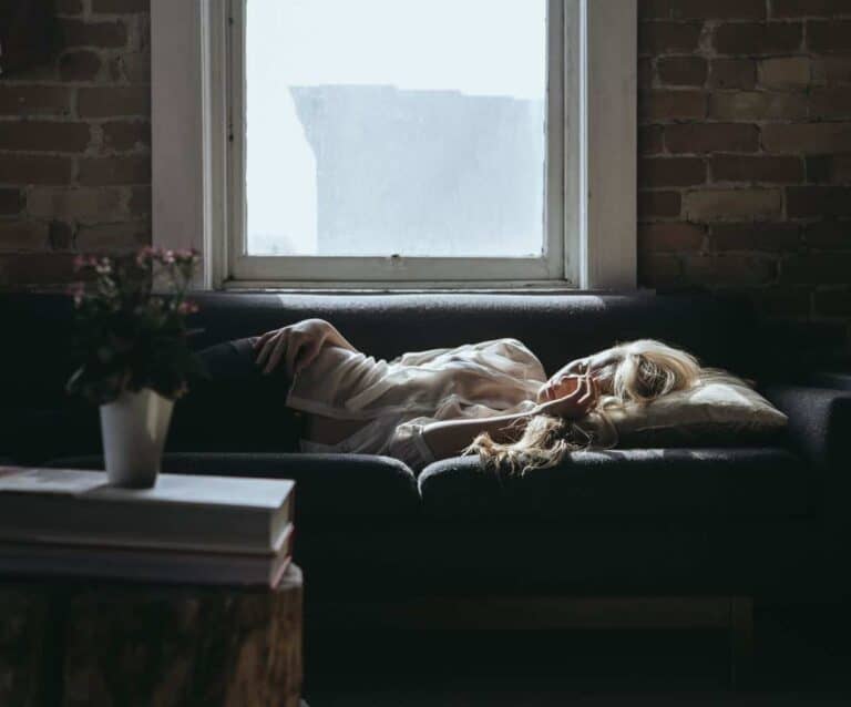 A cat sitting on top of a bed next to a window