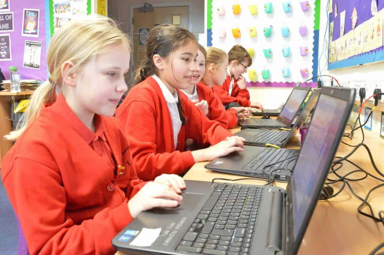 A young boy using a laptop computer sitting on top of a table