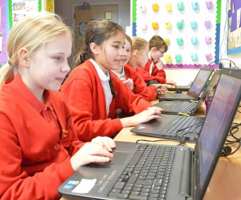 A young boy using a laptop computer sitting on top of a table