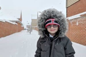 A person wearing a hat with snow on the ground posing for the camera