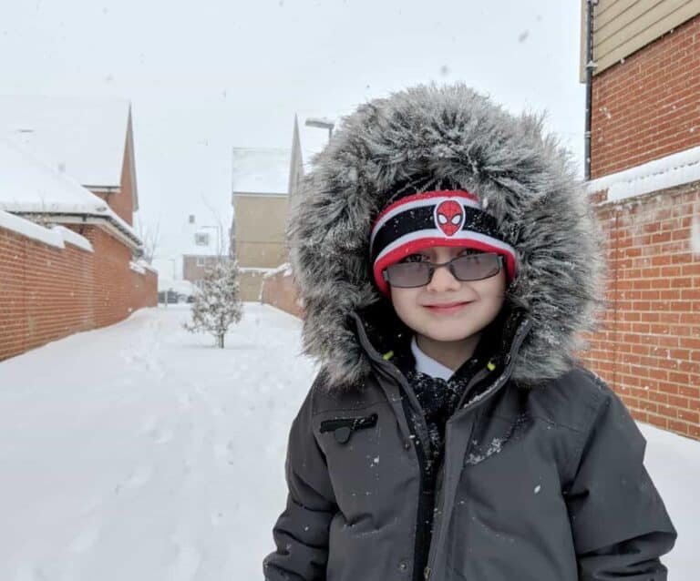 A person wearing a hat with snow on the ground posing for the camera