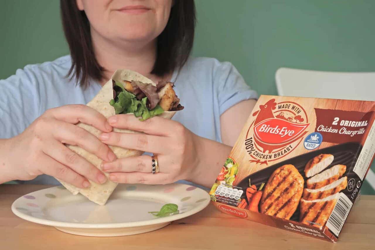 A woman sitting at a table eating a sandwich