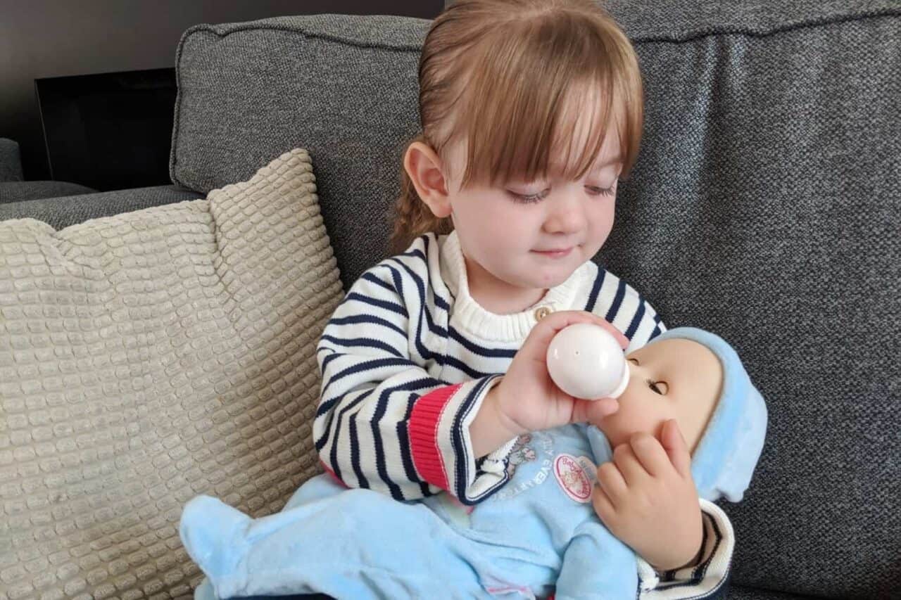 A small child sitting on a couch holding a baby