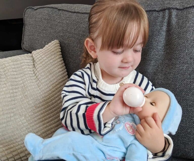 A small child sitting on a couch holding a baby