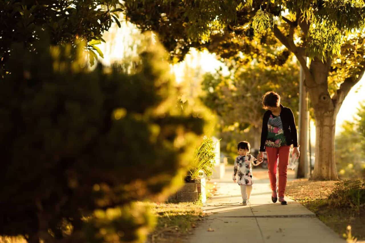 A man riding a skateboard down a sidewalk next to a tree