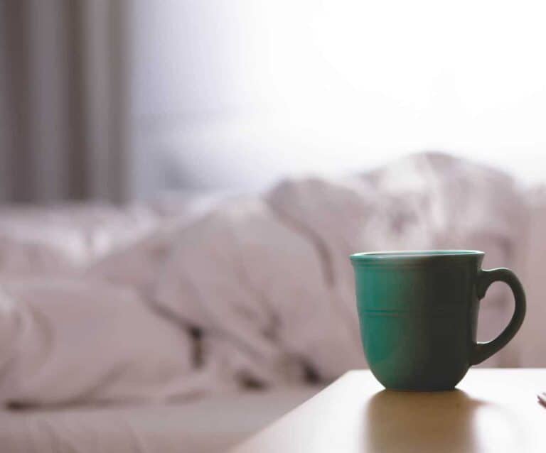 A cup of coffee sitting on top of a bed