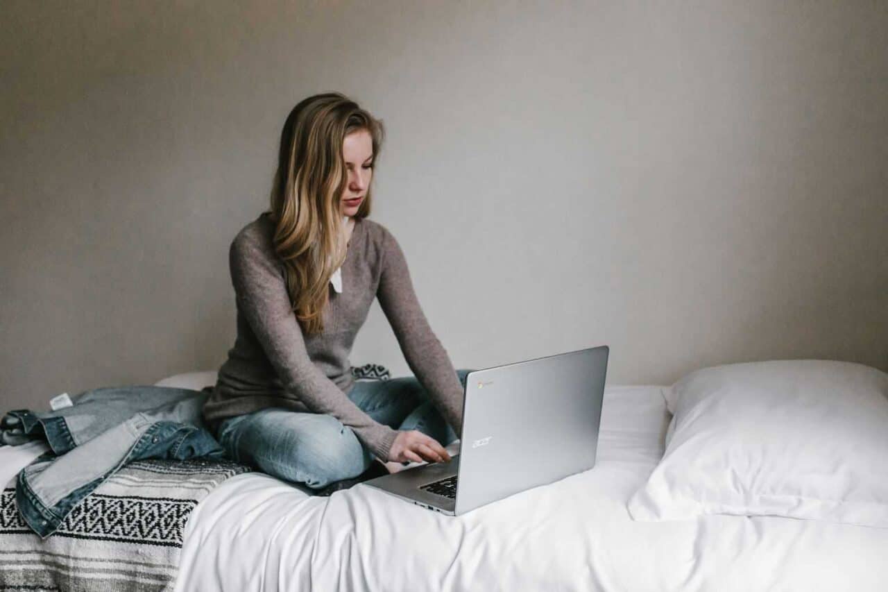 A person sitting on a bed using a laptop