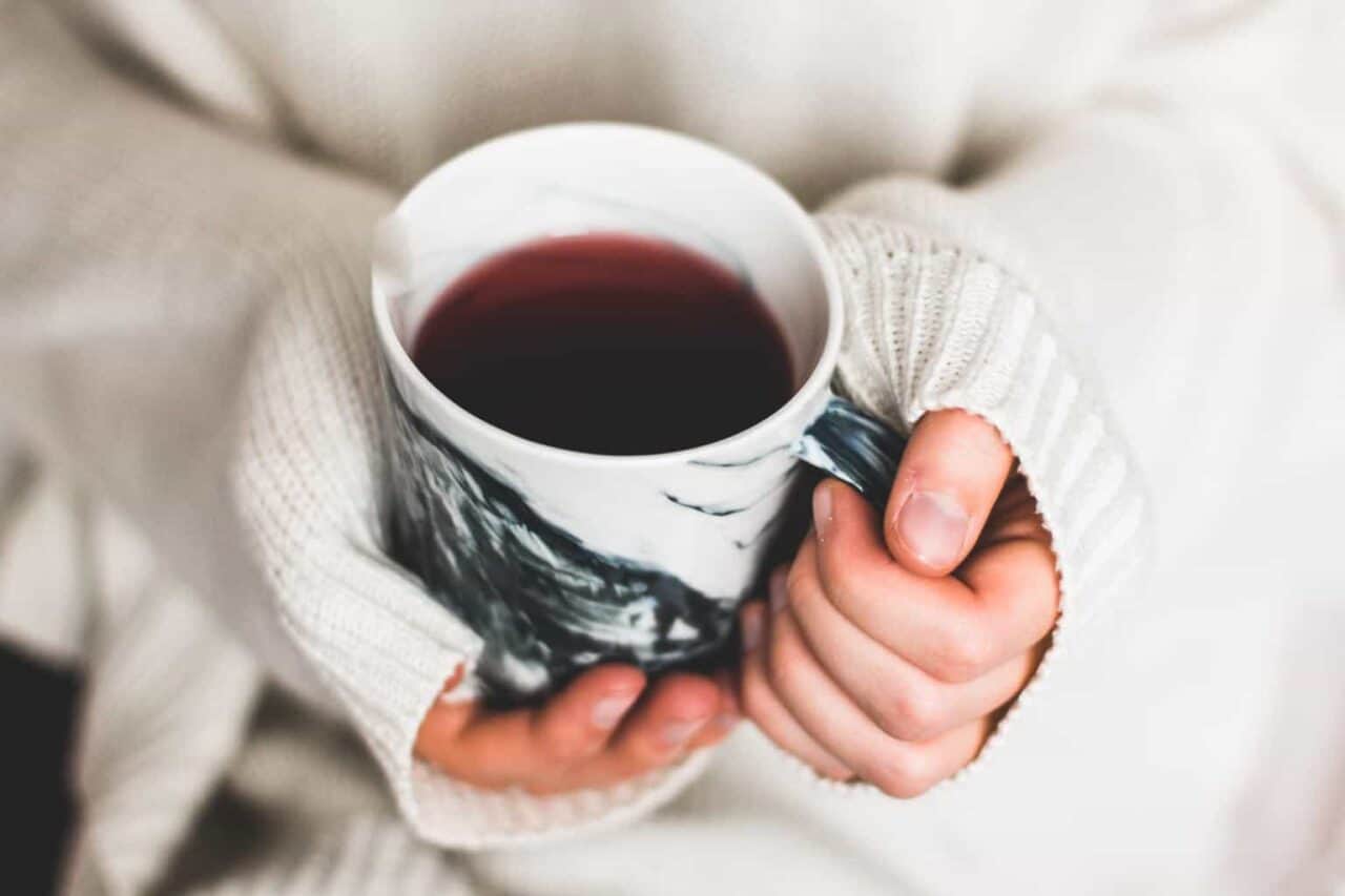 A close up of a person holding a cup of coffee