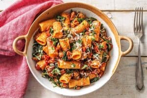 A bowl of food on a plate, with Pasta and Sausage