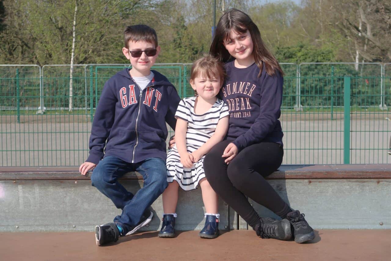 A couple of people that are sitting on the side of a fence