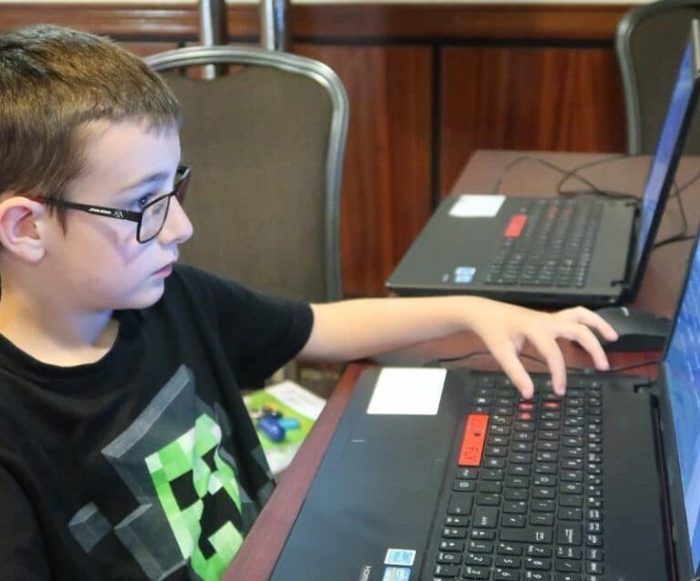 A man using a laptop computer sitting on top of a table