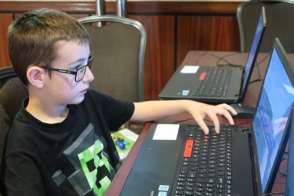 A man using a laptop computer sitting on top of a table