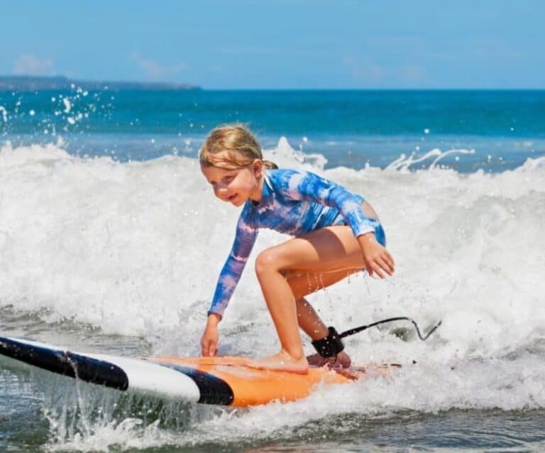 A young girl riding a wave on a surfboard in the water