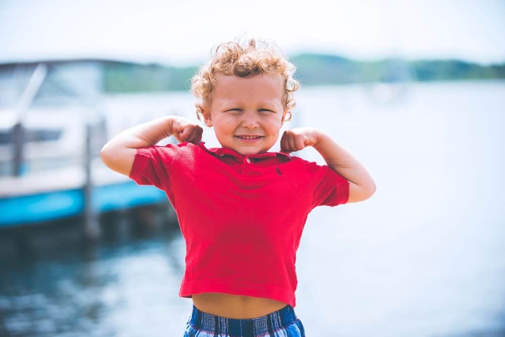 A little girl standing next to a body of water