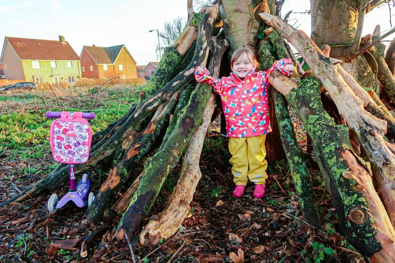 A little girl standing next to a tree