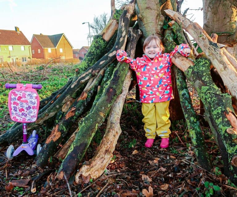 A little girl standing next to a tree