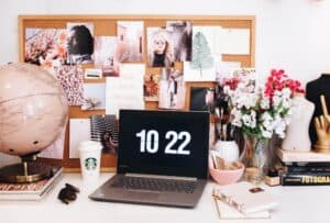 A desk with a laptop and a vase of flowers on a table