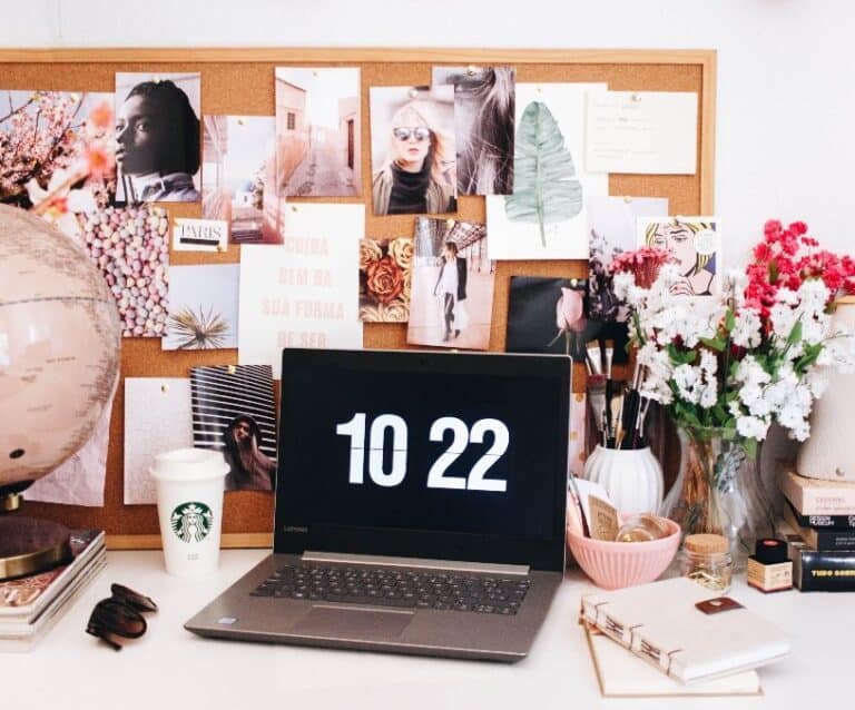 A desk with a laptop and a vase of flowers on a table