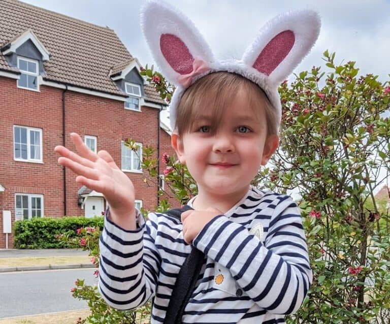 A young girl wearing bunny ears standing in front of a building