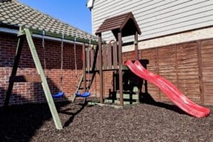 A wooden climbing frame sitting on play bark