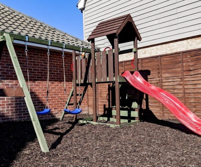 A wooden climbing frame sitting on play bark