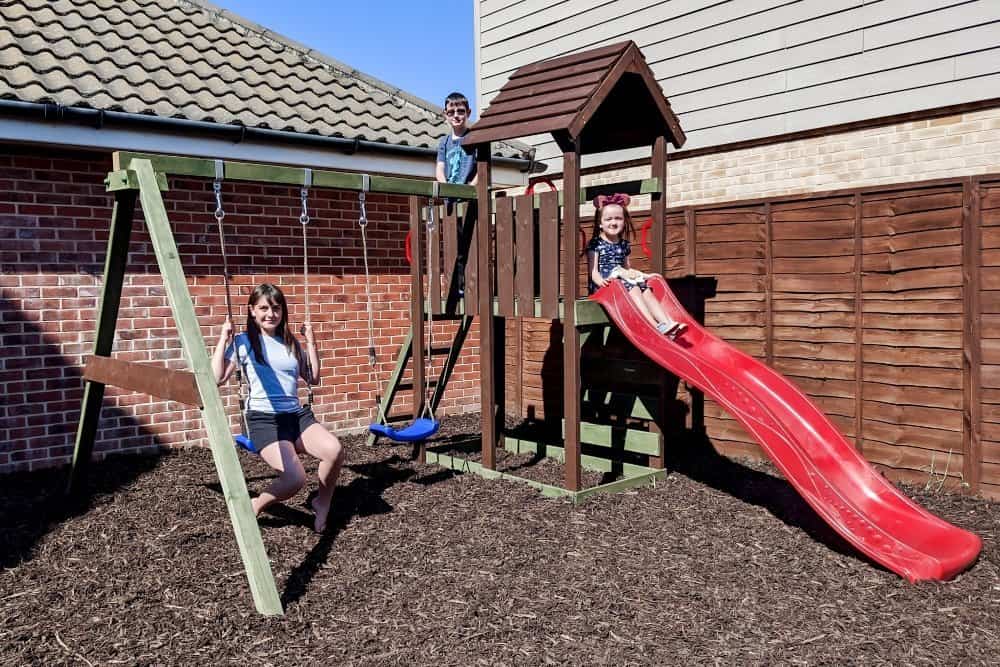 Children playing on a wooden climbing frame sitting on play bark